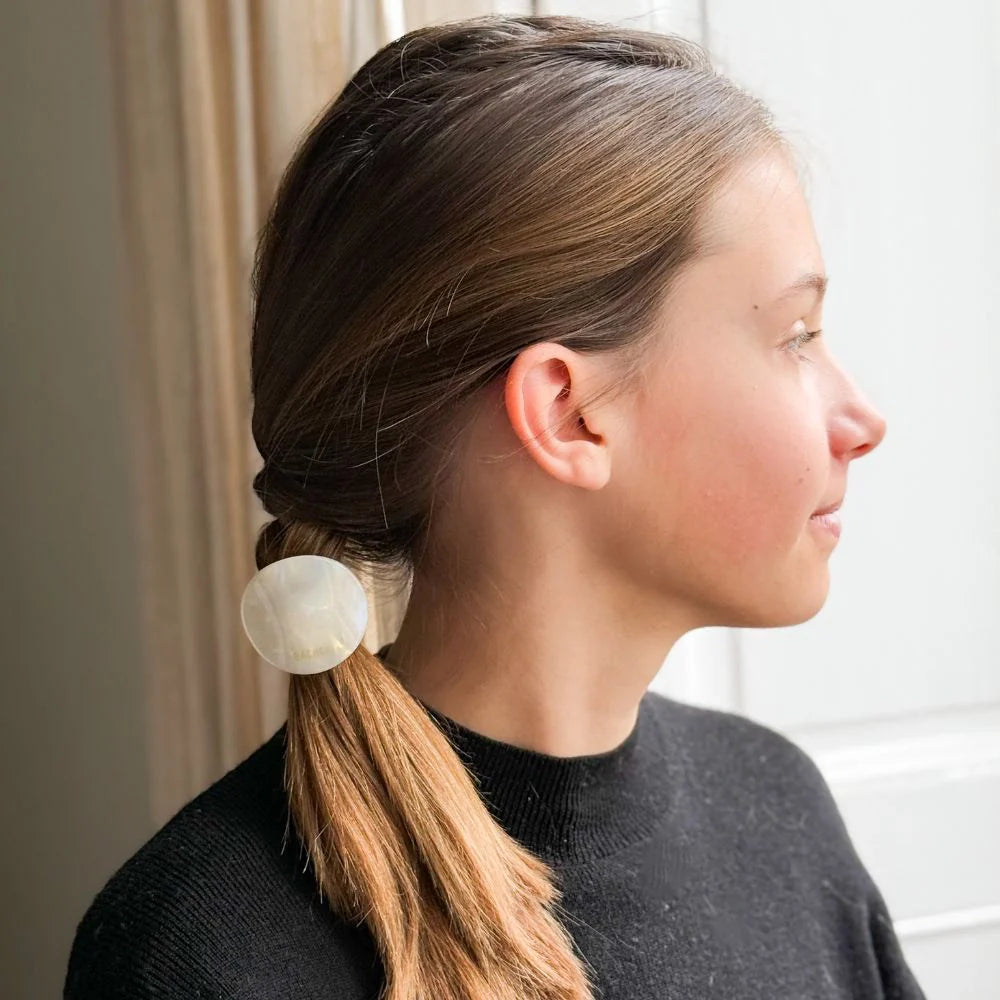 Young woman in profile wearing a sleek low braid secured with a Bachca plate elastic, showcasing a minimalist and elegant look.