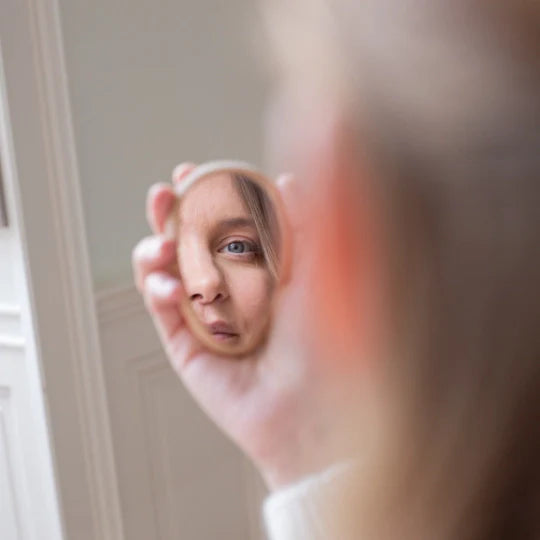 Woman holding Bachca Compact Mirror in her hand and she stares at her face in the mirror 