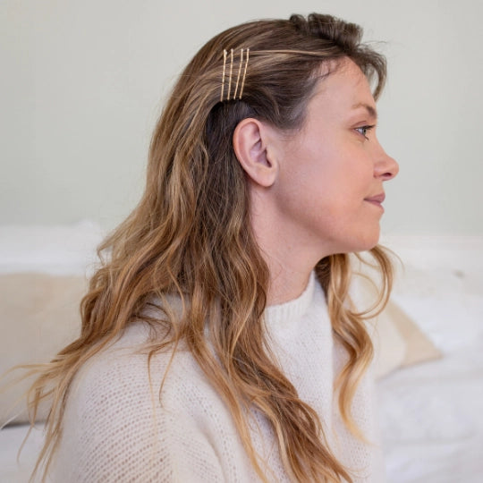 Woman with wavy hair  wearing Bachca gold bobby pin against a neutral background