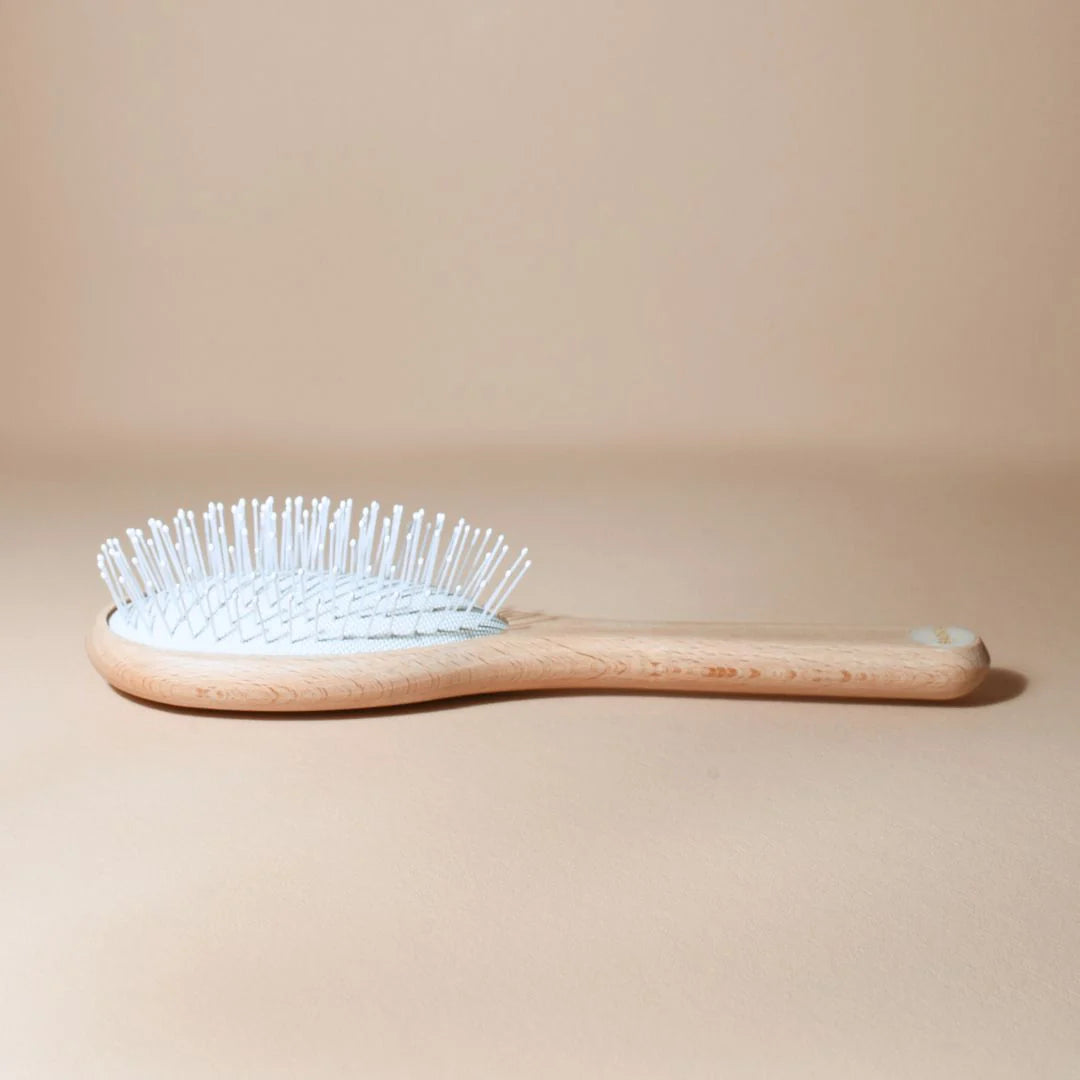 Bachca Everyday Detangling Hair Brush, small size in raw beechwood, side view with rounded white nylon bristles, placed on a beige background.