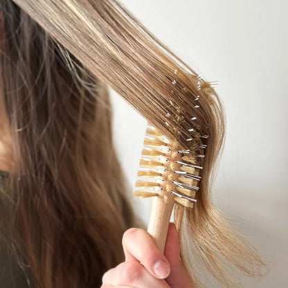 Brushing hair with the Bachca round wooden brush for a natural and gentle blowout.