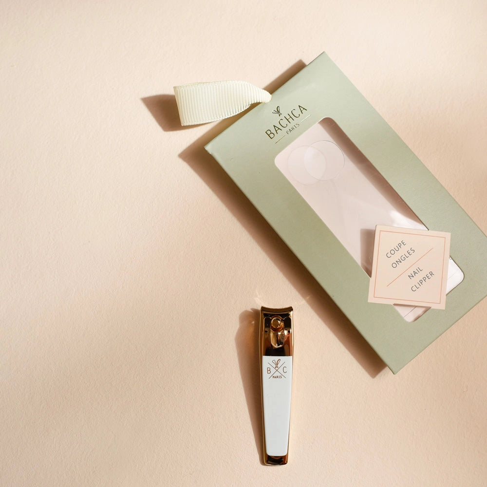 Gold Nail Clipper on beige background with package 