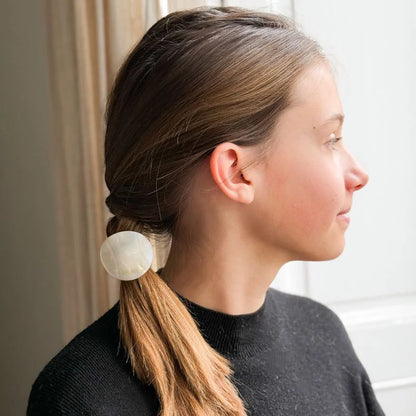 Young woman in profile wearing a sleek low braid secured with a Bachca plate elastic, showcasing a minimalist and elegant look.