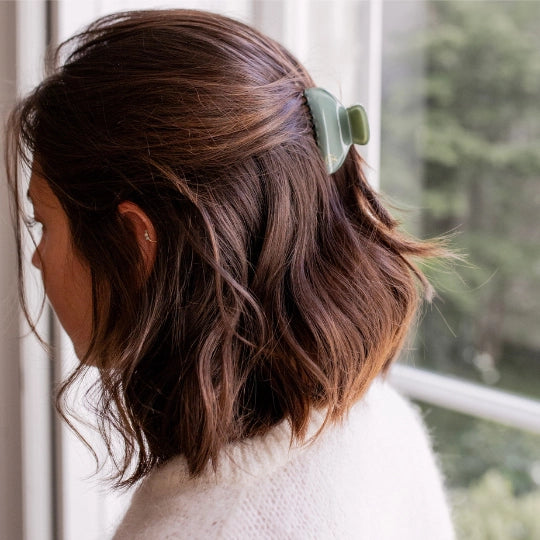 Person with wavy hair wearing Seafoam Green Opaline Claw Clip, standing indoors with a blurred natural background
