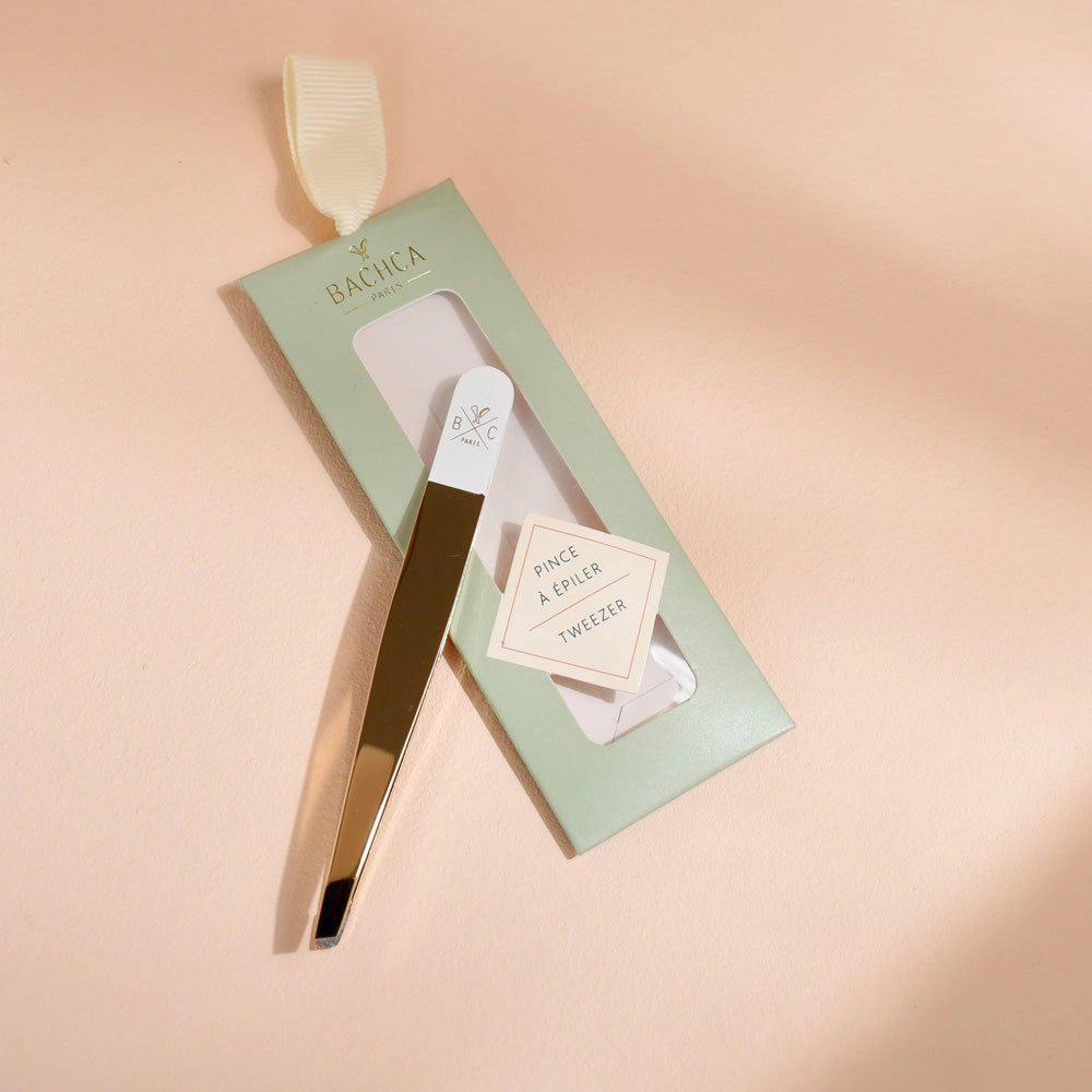 Eyelash tweezer set with packaging on a beige background